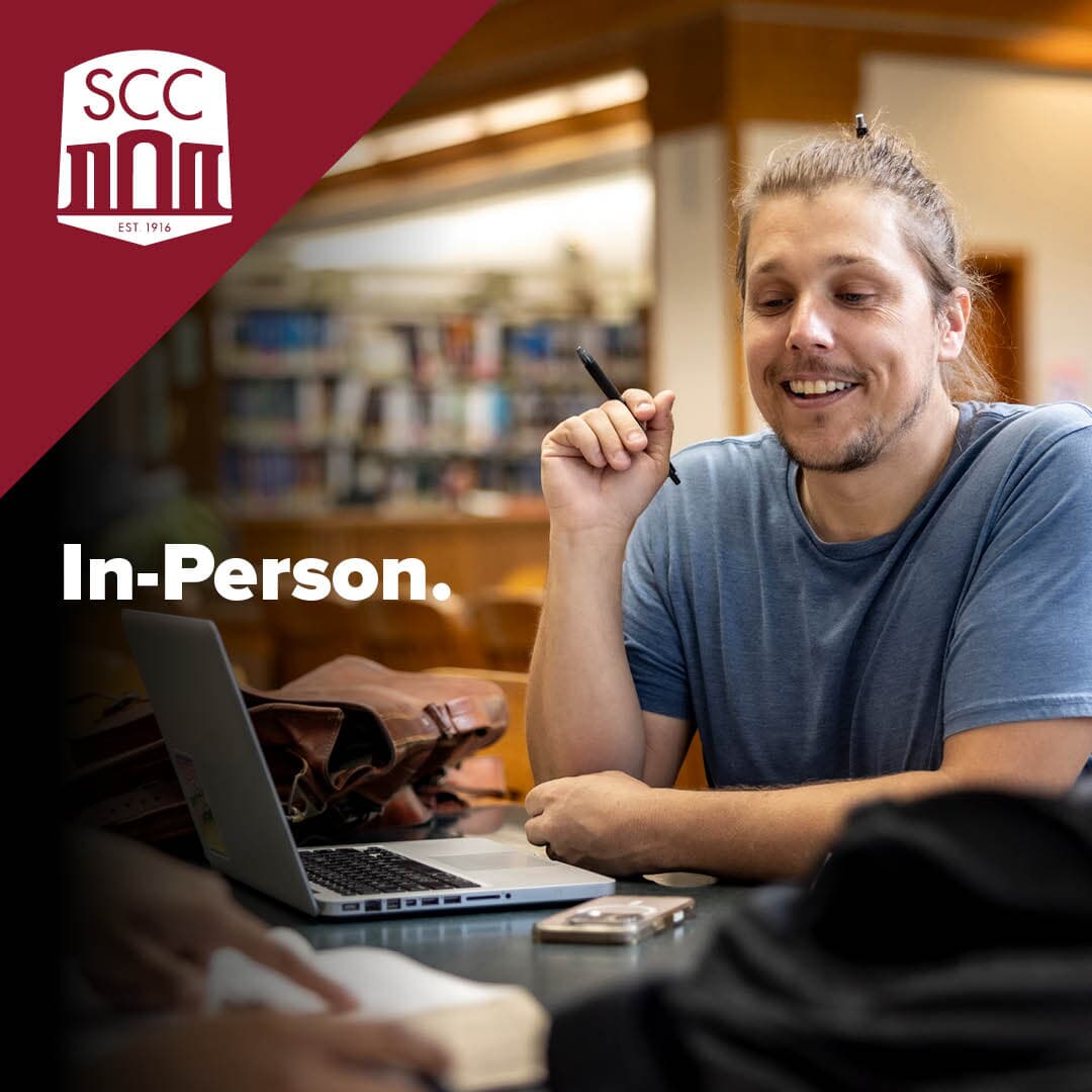 Text over photo of smiling man sitting at a desk that says In Person next to SCC logo